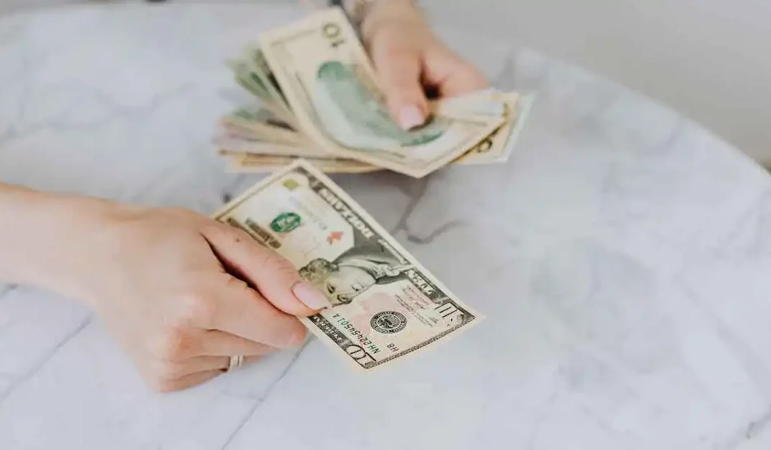 Person counting cash at home to cover end-of-month expenses