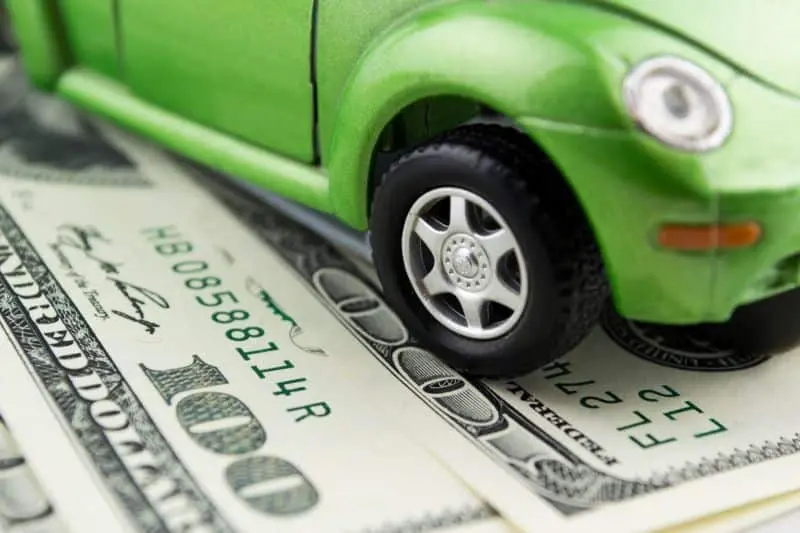 green volkswagen beetle model car sitting on top of cash, hundred dollar bills